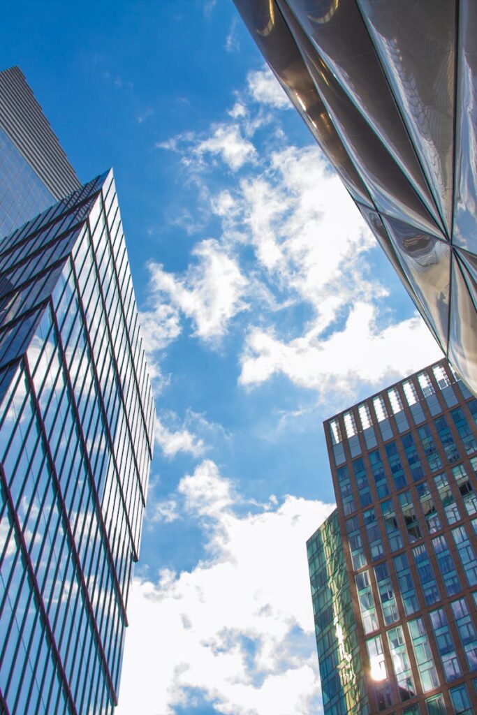 A low angle view of modern skyscrapers with glass facades against a clear blue sky in New York City.